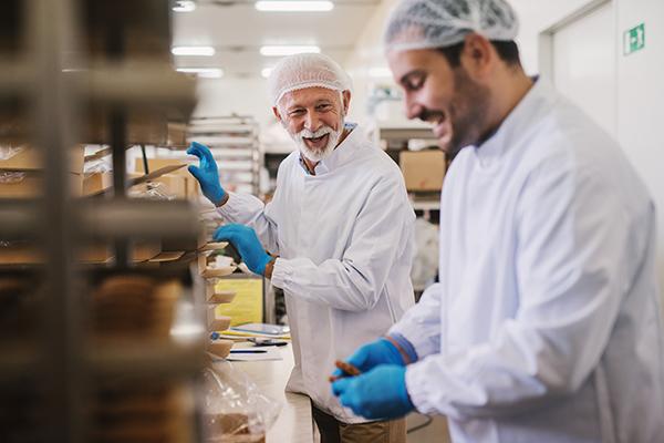 Deux personnes qui portent un casque et des gants travaillent dans une boulangerie